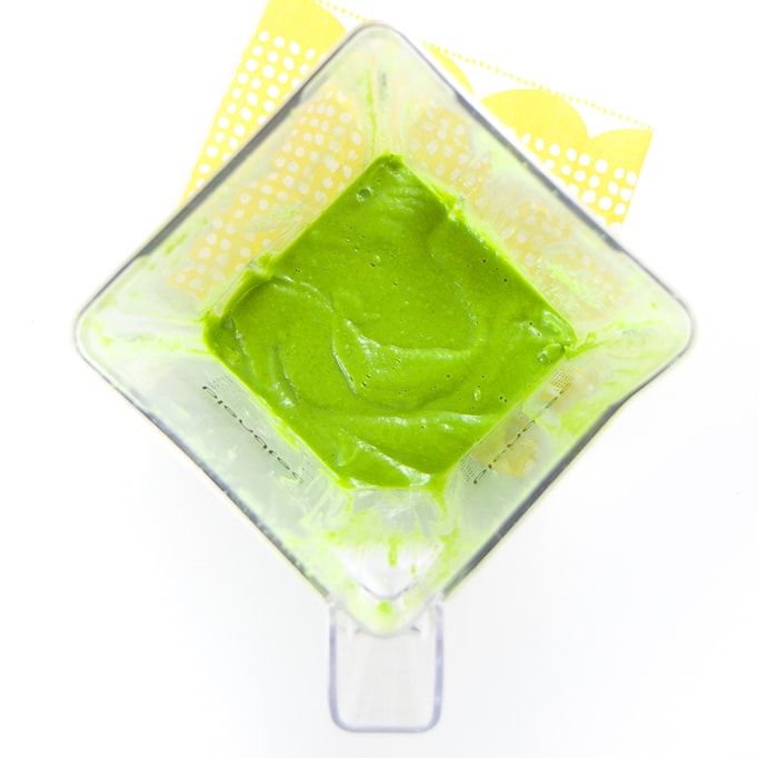A clear blender filled with a smooth green baby food puree.