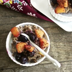small bowl with oatmeal, peaches and blueberries inside for toddler.