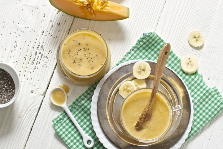 Bowls scattered on white board with homemade baby food puree.