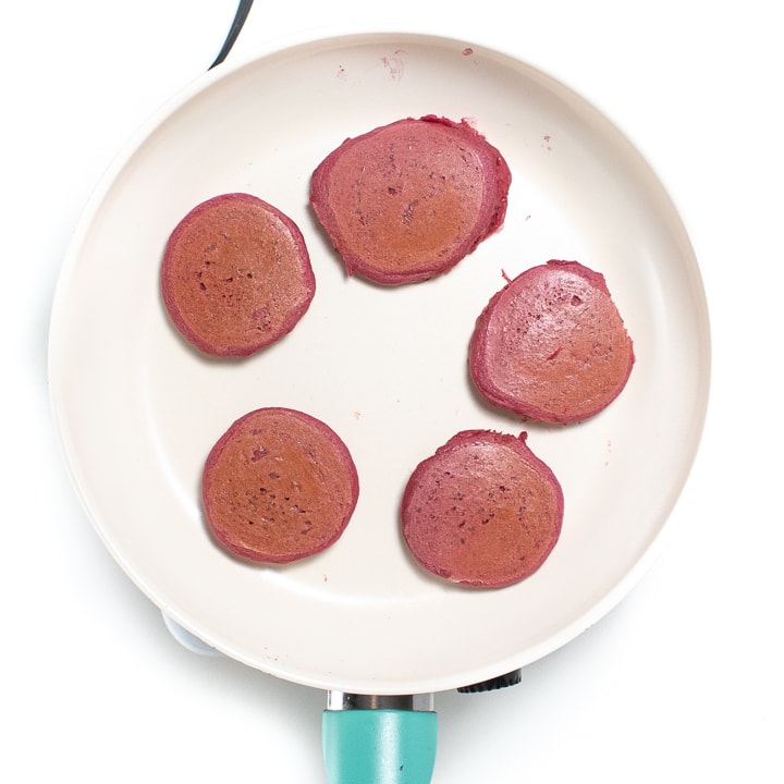 Small skillet with cooked pink pancakes on it.
