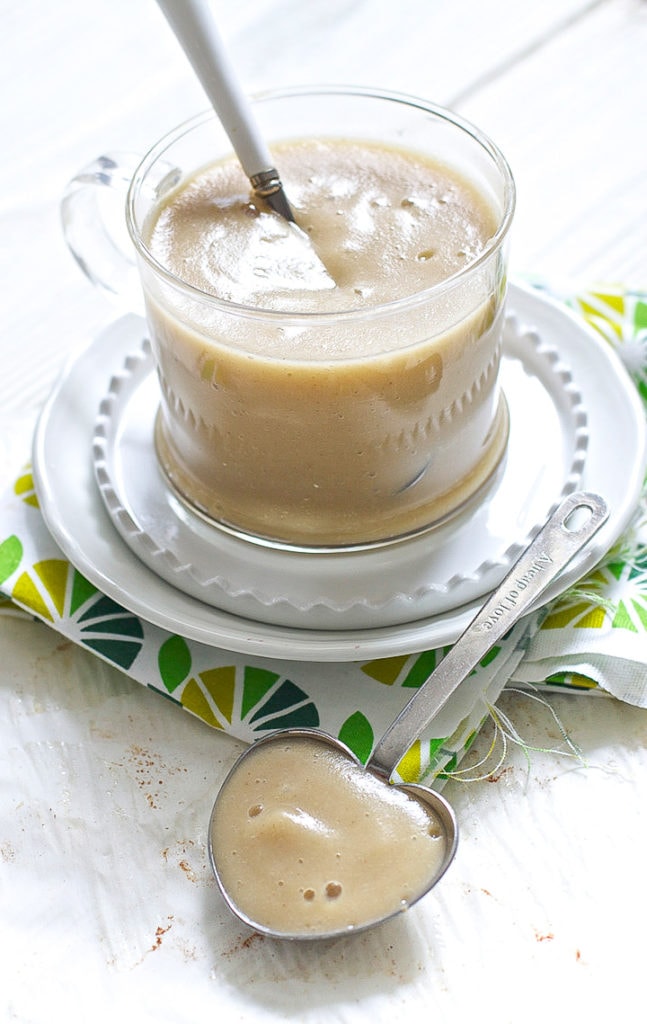 clear bowl filled with baby food puree with a spoon resting in front.