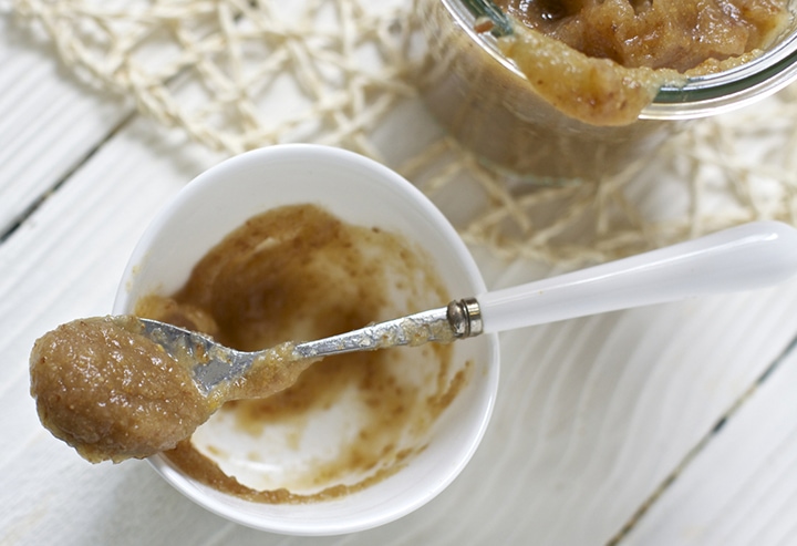 Small white bowl with a baby spoon resting on top filled with baby food.