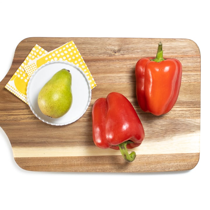 Red pepper and pear on a cutting board.