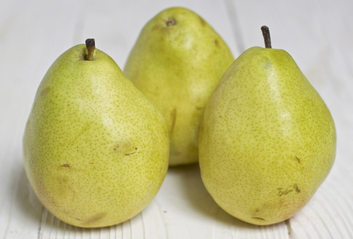 3 pears standing on a white board.