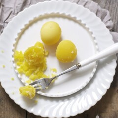 3 cooked egg yolks on a white plate with a fork holding part of one of the yolks.