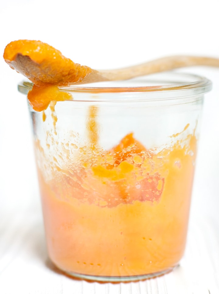 Clear jar of peach and carrot baby food puree.