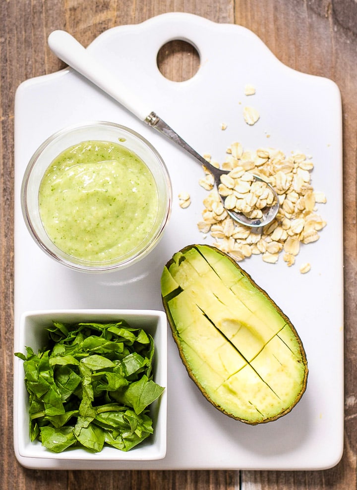 Image is of a white cutting board with a spread of produce and a small bowl filled with a healthy homemade puree.