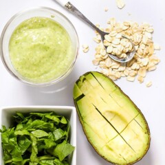 Image is of a white cutting board with a spread of produce and a small bowl filled with a healthy homemade puree.
