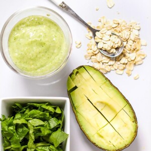 Image is of a white cutting board with a spread of produce and a small bowl filled with a healthy homemade puree.