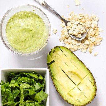 Image is of a white cutting board with a spread of produce and a small bowl filled with a healthy homemade puree.