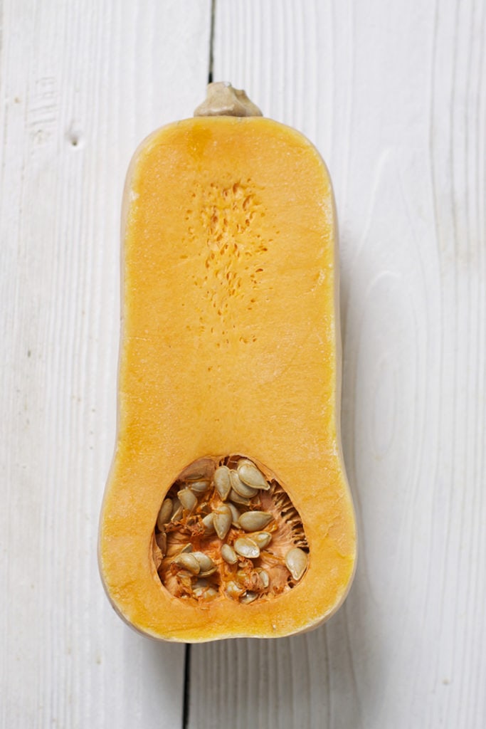 Butternut squash cut in half on a white board.