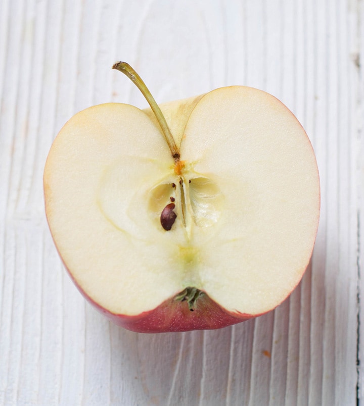 Apple cut in half on a white board.
