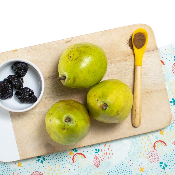 Cutting board with pears, dried prunes and cloves.