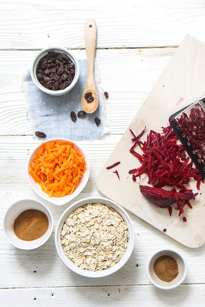 Spread of beets, carrots, oats, raisins and spices on a white board.