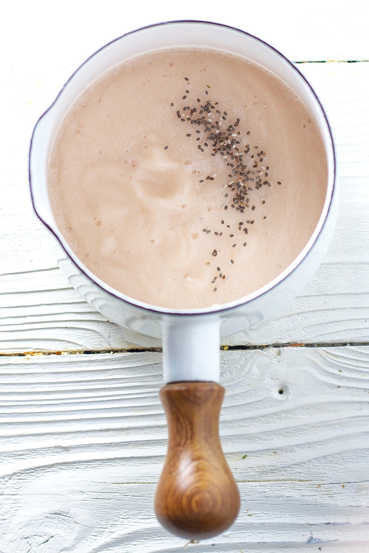Small white saucepan filled with a pink baby food puree.
