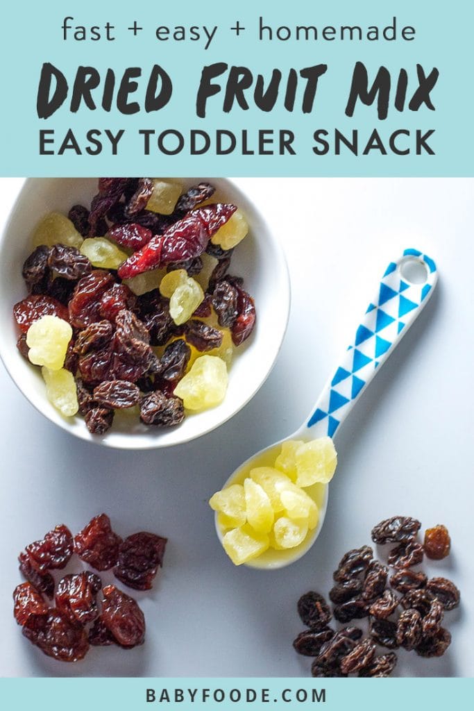 A bowl of dried fruit mix with a toddler spoon on a white background.