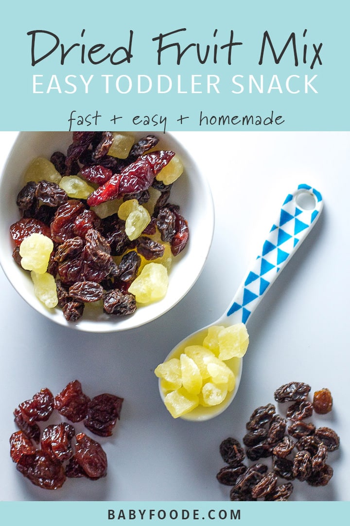 A bowl of dried fruit mix with a toddler spoon on a white background.