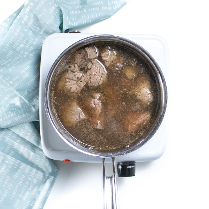 Saucepan with cooked beef inside.