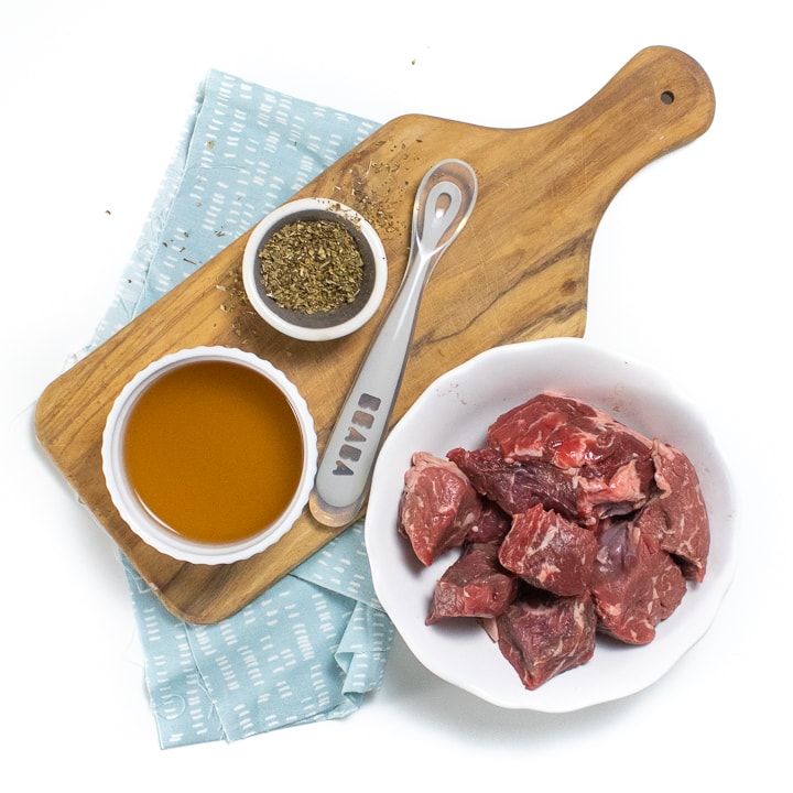 Spread of ingredients needed for this recipe - beef, dried herbs and broth.