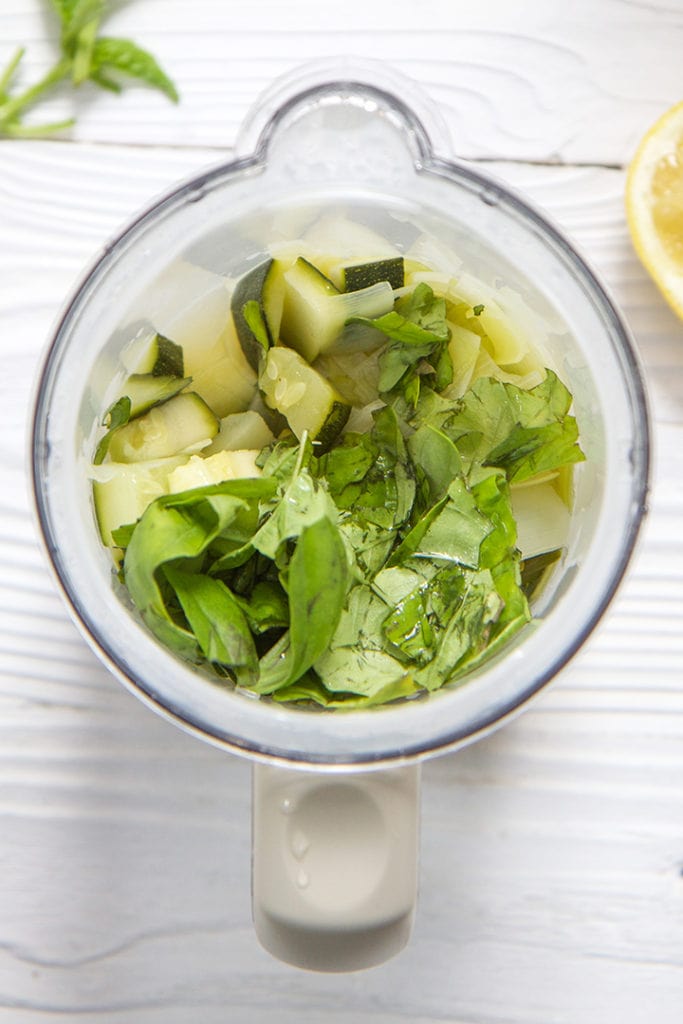 Steamer basket with cooked green veggies inside.