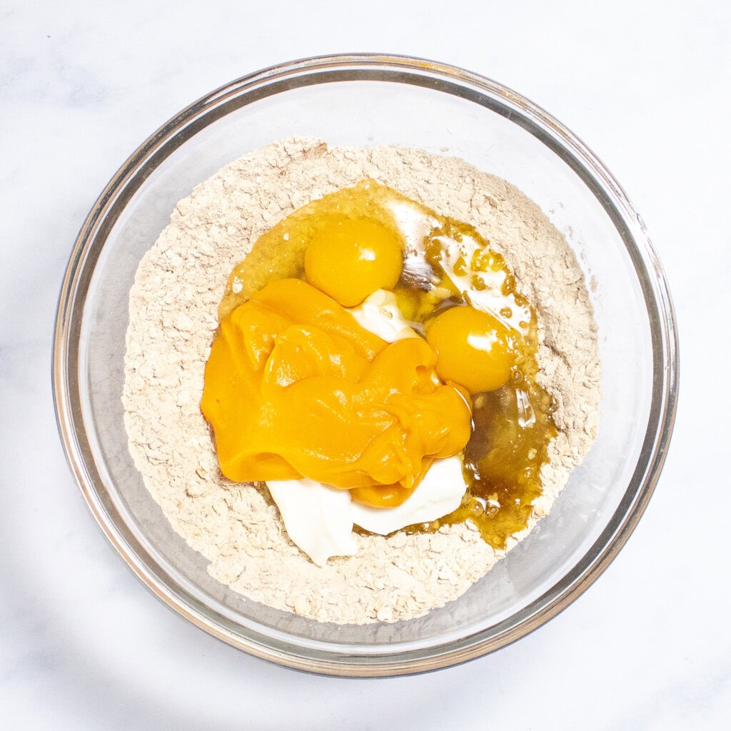 Clear glass bowl with dry and wet sweet potato ingredients inside.