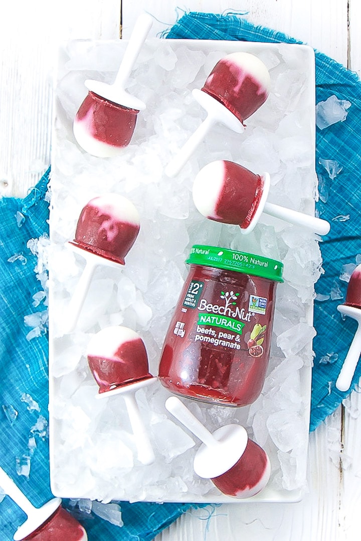 Tray of ice with popsicles and baby food jar laying on top.