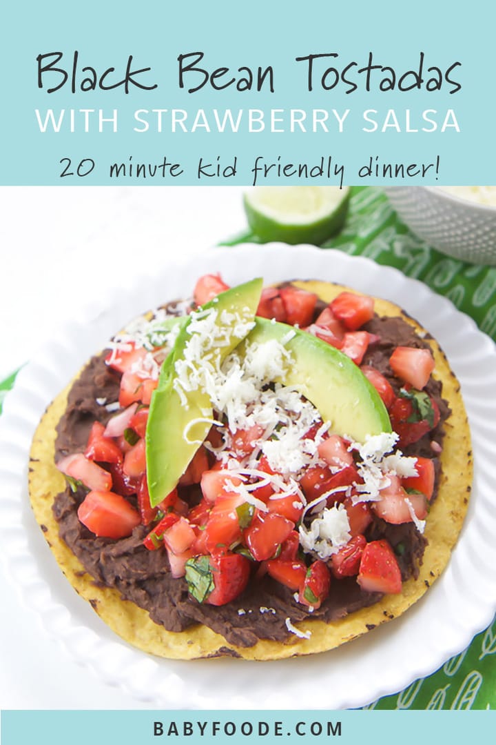A black bean tostadas topped with strawberry salsa and a avocado on a white plate.