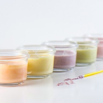 Clear jars of colorful finger paints lined up in a row.