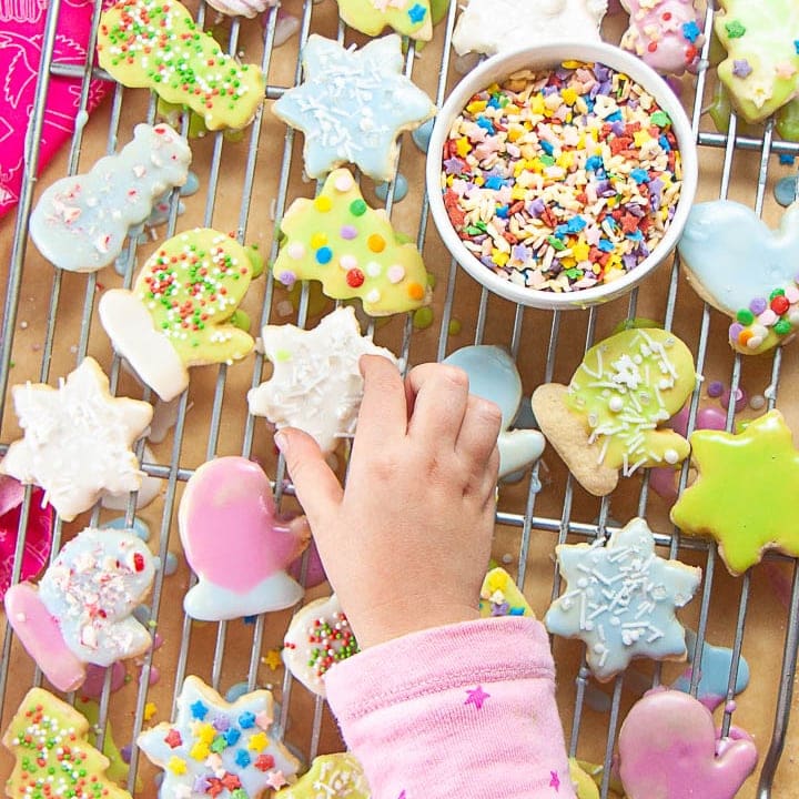 Small kids hands reaching for a sugar cookie.