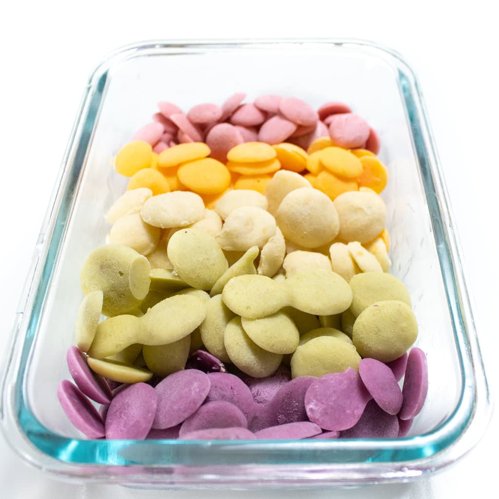 A glass container full of a rainbow assortment of yogurt melts for baby