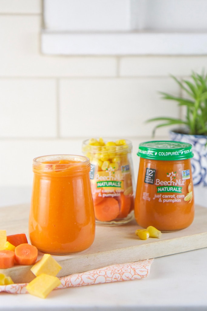3 jars of baby food sitting on a counter - one with ingredients, one store bought, one filled with homemade puree.