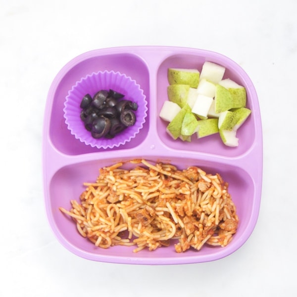 toddler dinner plate with cut up pasta, fruit and olives