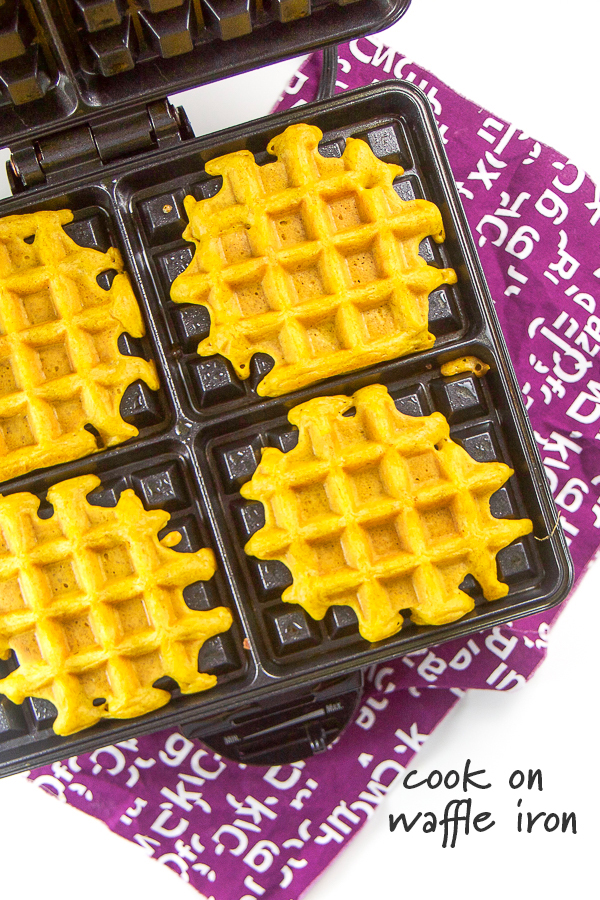 Golden milk waffles cooking in a waffle iron.