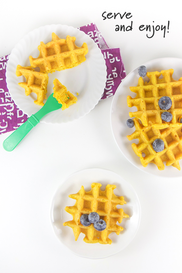 Golden milk waffles on white plates with fresh blueberries.
