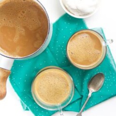 Two mugs of turmeric cocoa on a blue cloth.