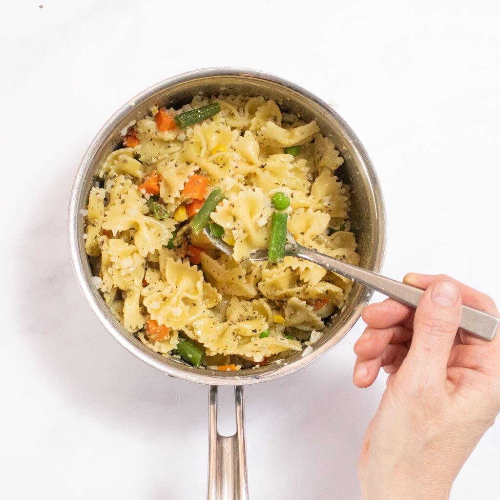 A silver saucepan on my counter with the pasta and veggies with a basil sauce.