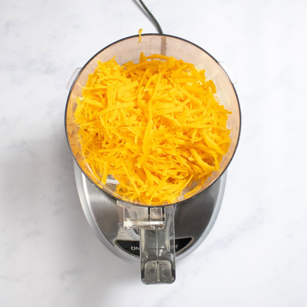 Food processor on my kitchen counter full of shredded cheese.