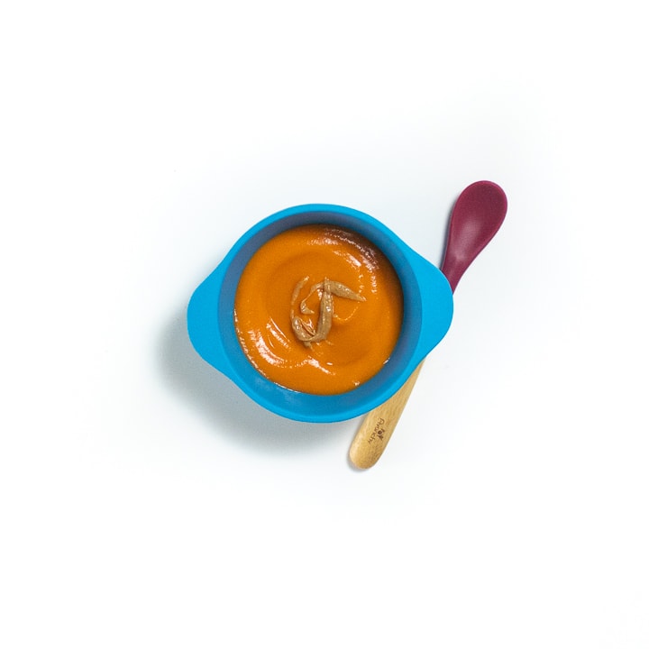 Blue baby bowl with a stage two puree with peanut butter in it.
