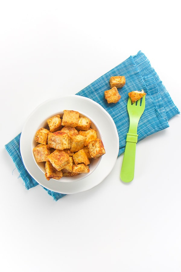 white bowl filled with cubes of seasoned tofu onto of a blue napkin.