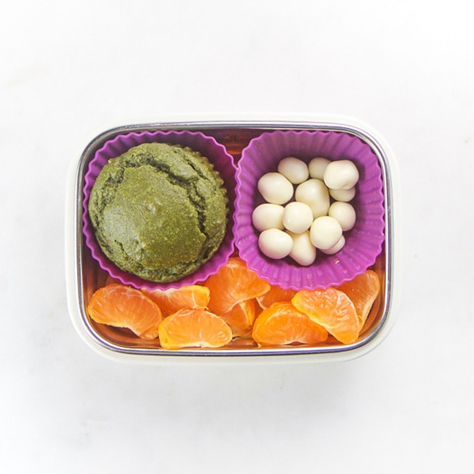 Rectangle kids bento box - green muffin, yogurt covered raisins, mandarin oranges sections.