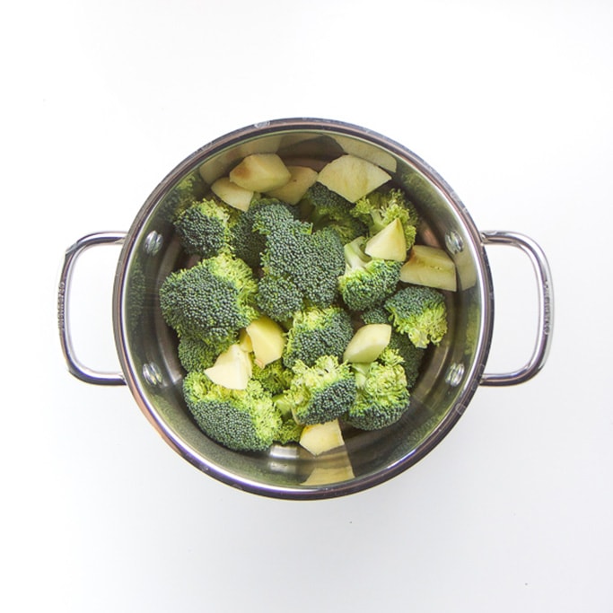 silver steamer basket filled with broccoli and a potato.