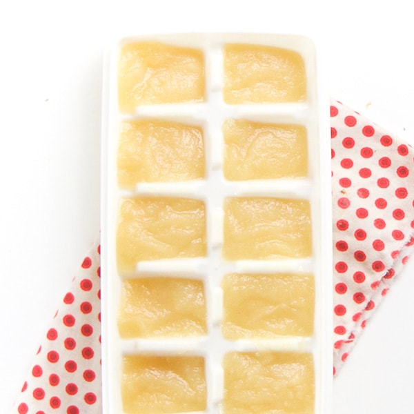A white ice cube freezer tray filled with a homemade baby food puree.