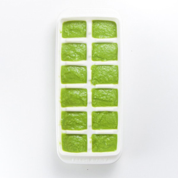 A white storage tray is filled with green bean baby food puree.