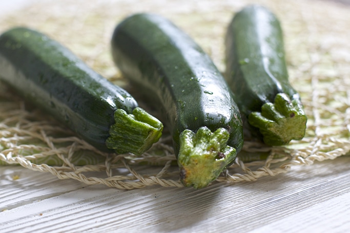 A side shot of 3 up close zucchinis from the root.