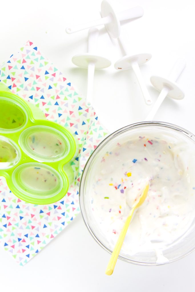 A clear bowl of funfeti yogurt, a green popsicle mold filled with yogurt.