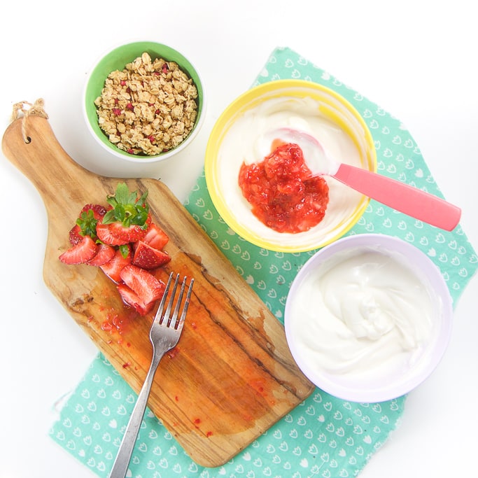 Smashed strawberries are mixed with plain yogurt for healthy parfait popsicles.