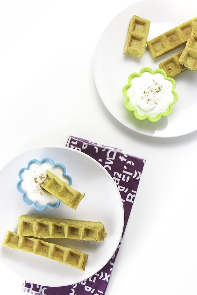 Overhead photo of 2 plates with pumpkin waffle dippers with cups filled with yogurt.
