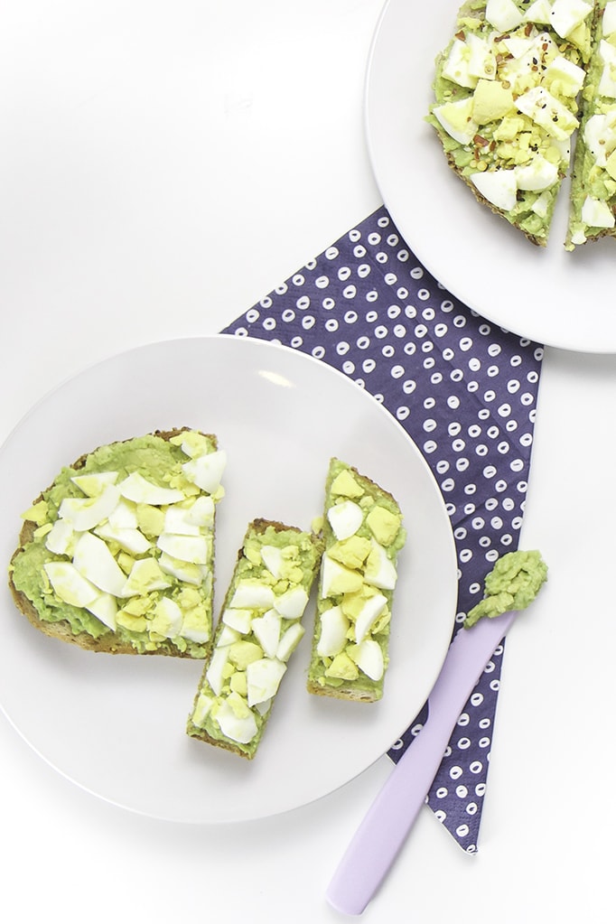 Two round white plates both filled with avocado and egg toast - one for baby and one for you.