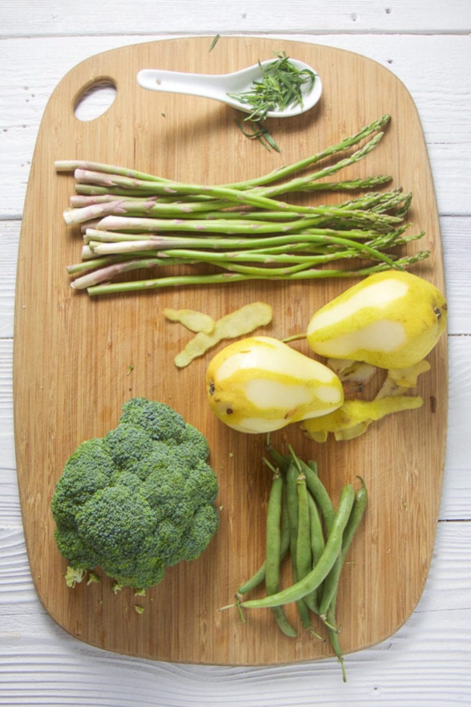 Cutting board with a spread of green veggies.