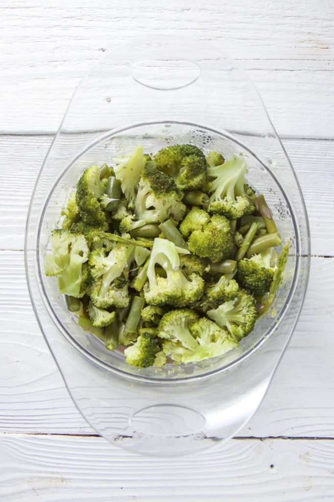 A steamer tray filled with broccoli, green beans and asparagus.